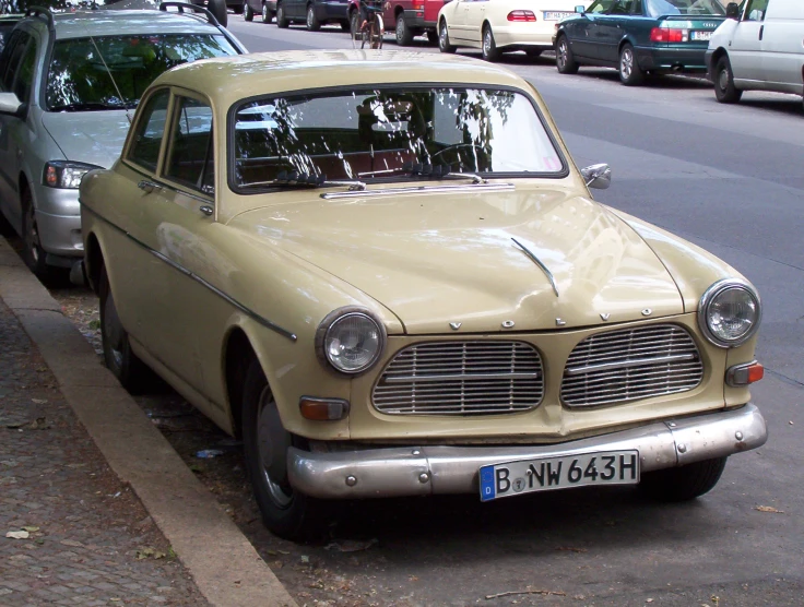 an old beige car parked on the side of the road