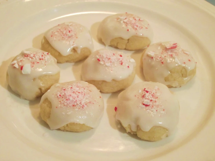 eight cookies with white frosting on a plate