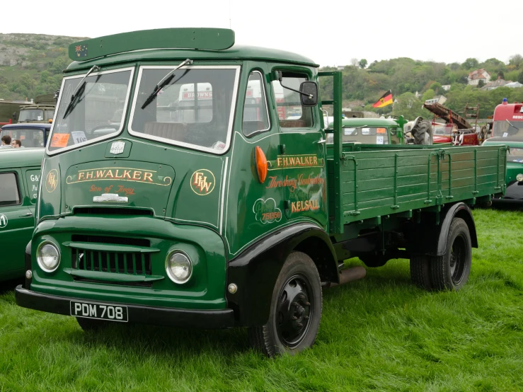 a row of old green trucks parked on a lush green field
