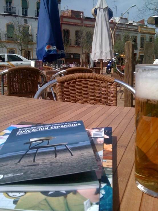 glass of beer on a table outside with magazines