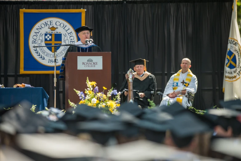 there are several graduates standing at the podiums in graduation attire