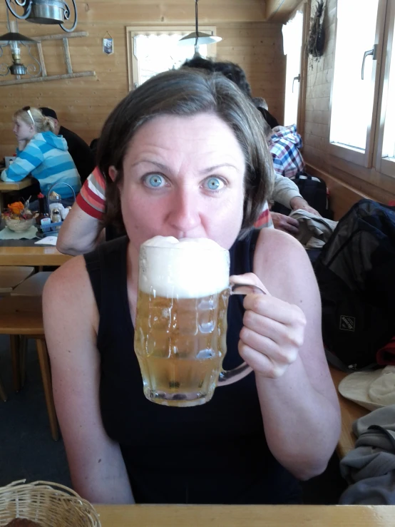 a woman drinking beer out of a tall glass