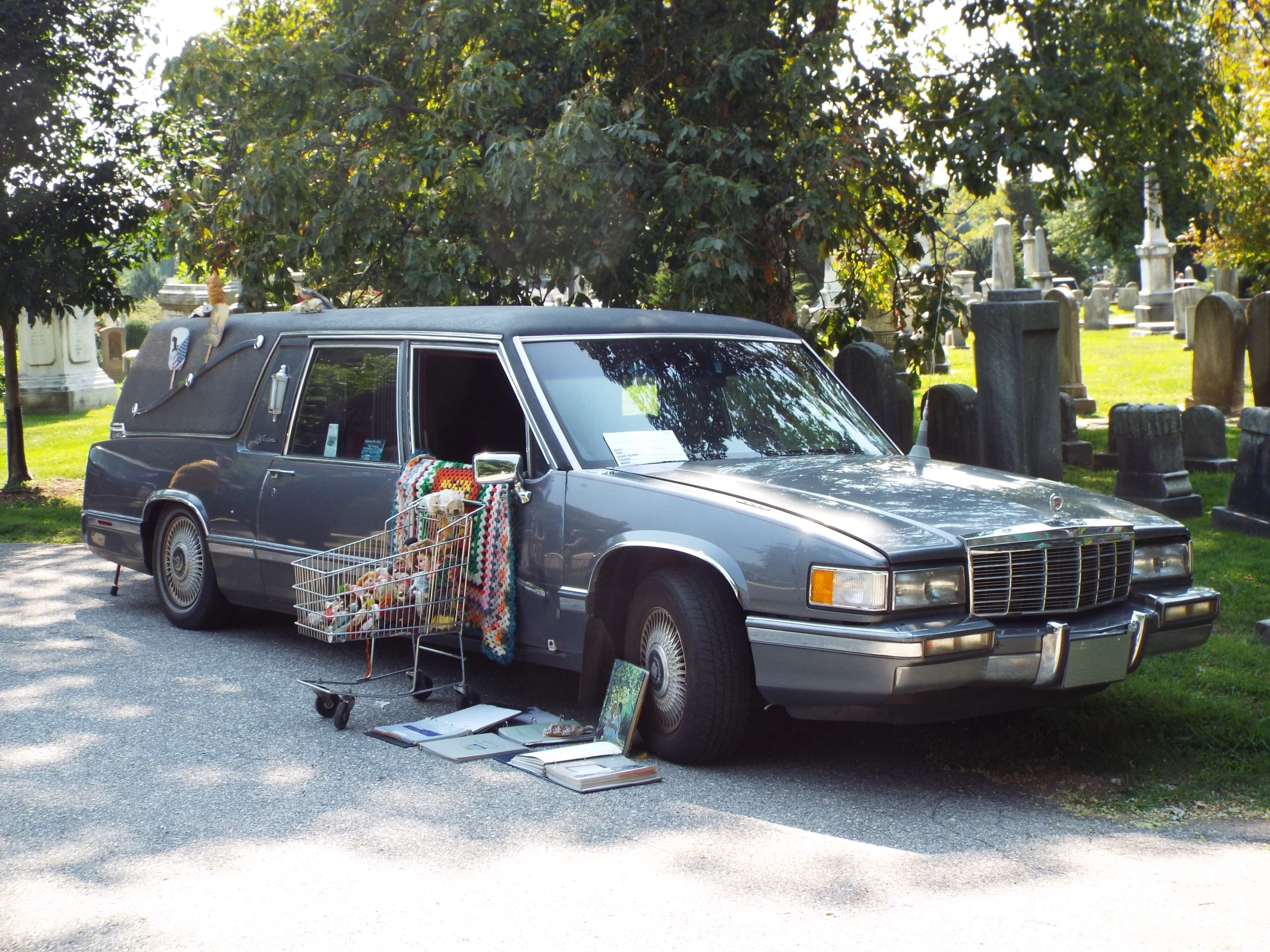 the old gray station wagon is parked beside an old cemetery