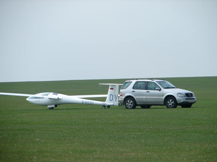 an airplane is parked near a van in the grass