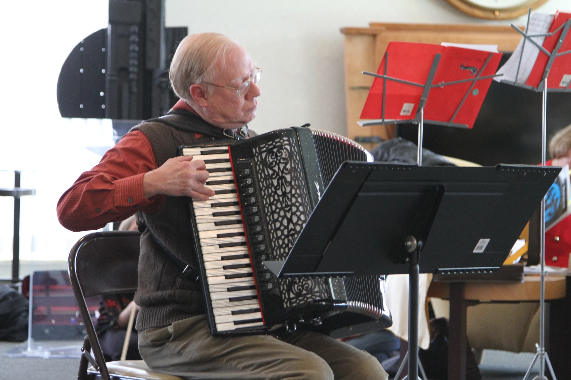 an elderly man playing the accordion next to the band