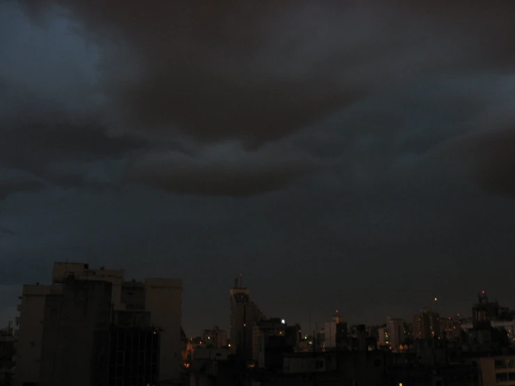 dark clouds loom above city lights in the distance