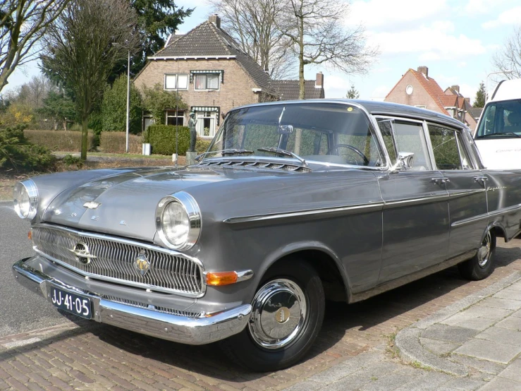 an old grey car parked in a parking lot