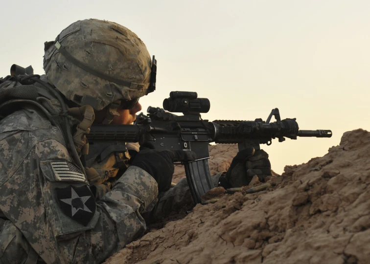 a man in camouflage is shooting with a rifle