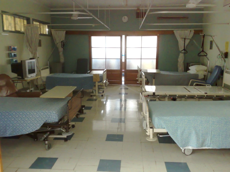 empty hospital room with beds, equipment and chairs