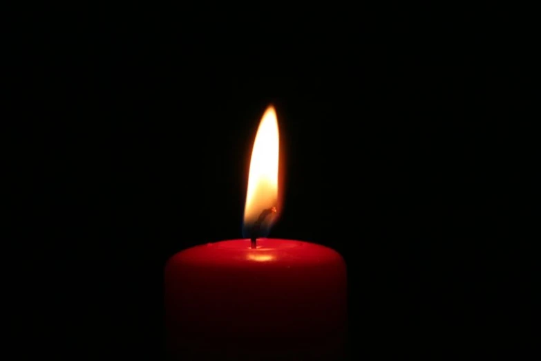 an empty red candle burning in the dark