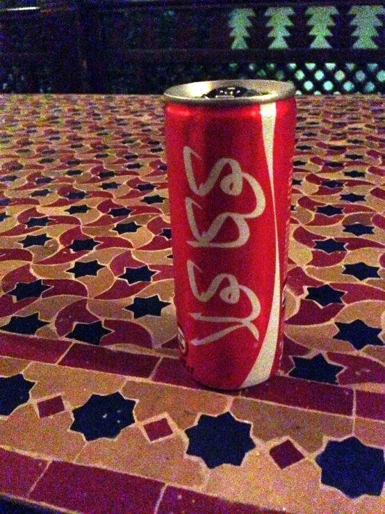 a red and white can sitting on top of a tiled table