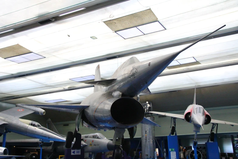 an airplane hanging up inside a museum with a few airplanes parked on the floor