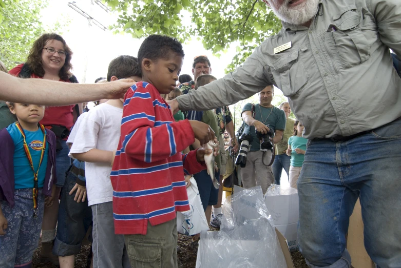 man handing over some white plastic bags to children