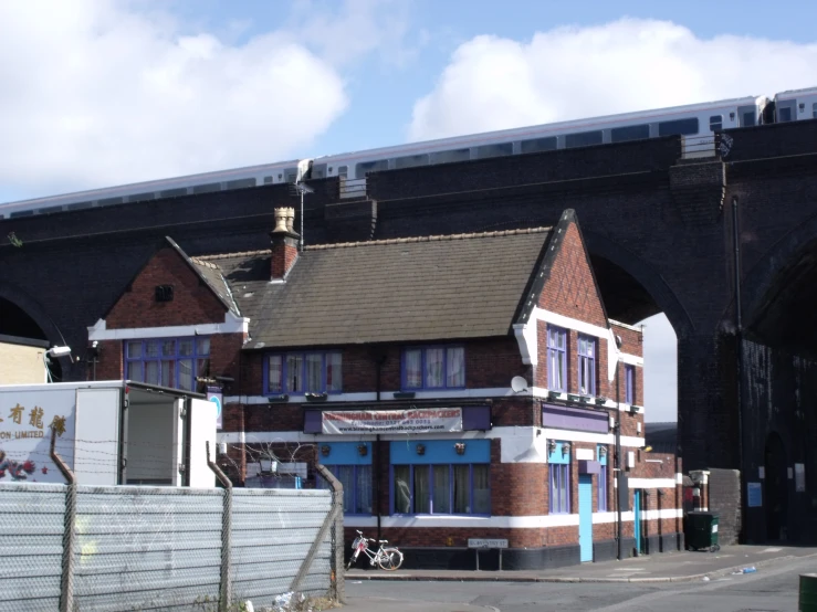 a train crossing a bridge over a building with a fence