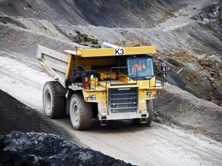 a large yellow truck is going down a dirt road