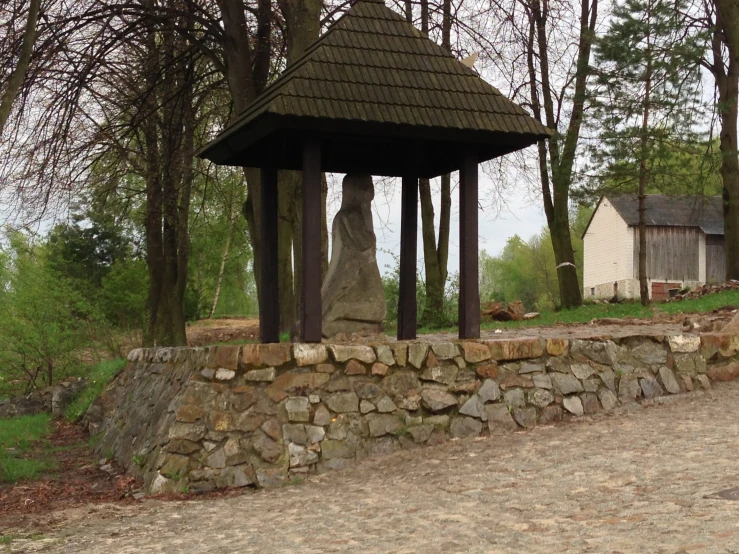 a stone wall next to a stone gazebo