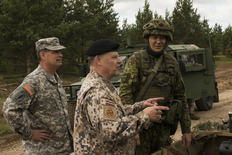 three military men standing by an army vehicle