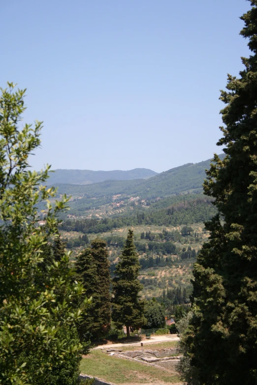 mountains, trees and a dirt path lead to the entrance