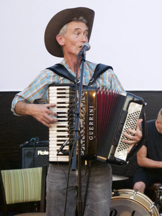 a man wearing a cowboy hat and holding an accordion