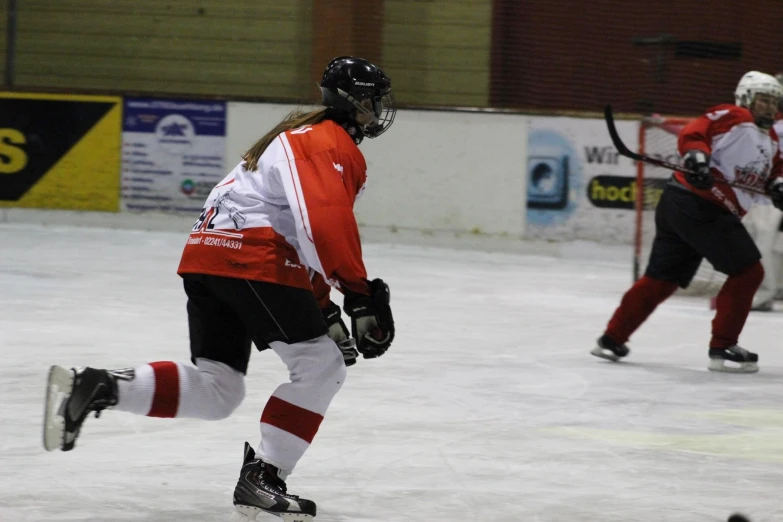 three people in hockey jerseys and helmets on a field