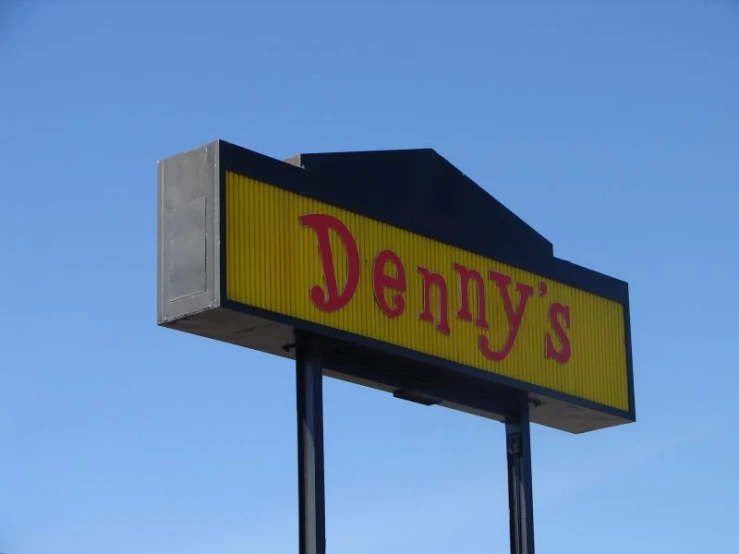 a sign for denny's sits on top of the roof