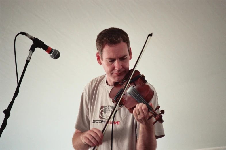 a man playing the violin near an microphone