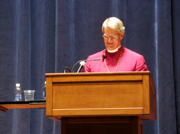 a priest stands at a podium speaking