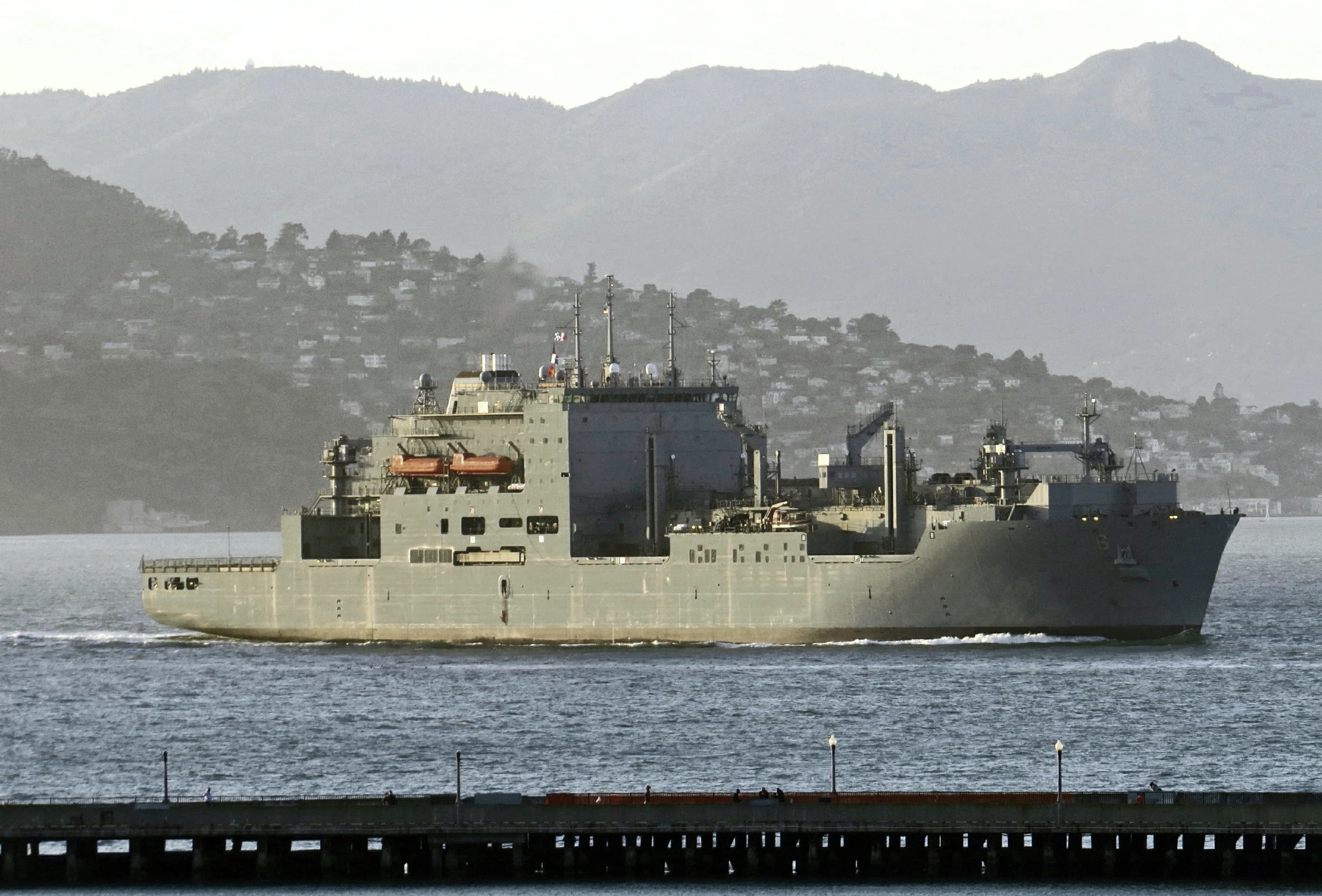 large ship moving fast in the ocean near a wharf