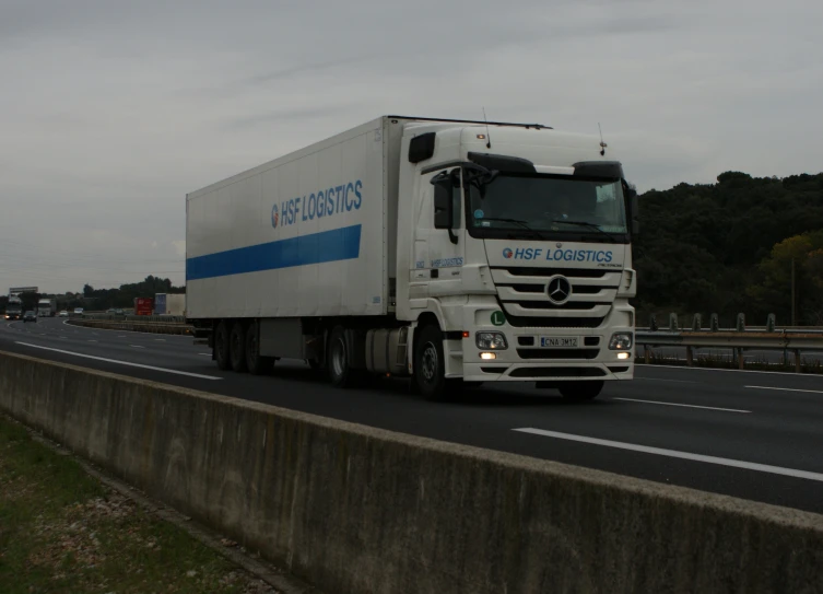 a white truck traveling on a freeway with trees in the background