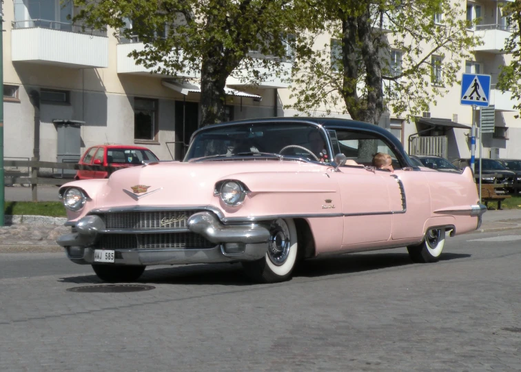 an old pink car is on a road