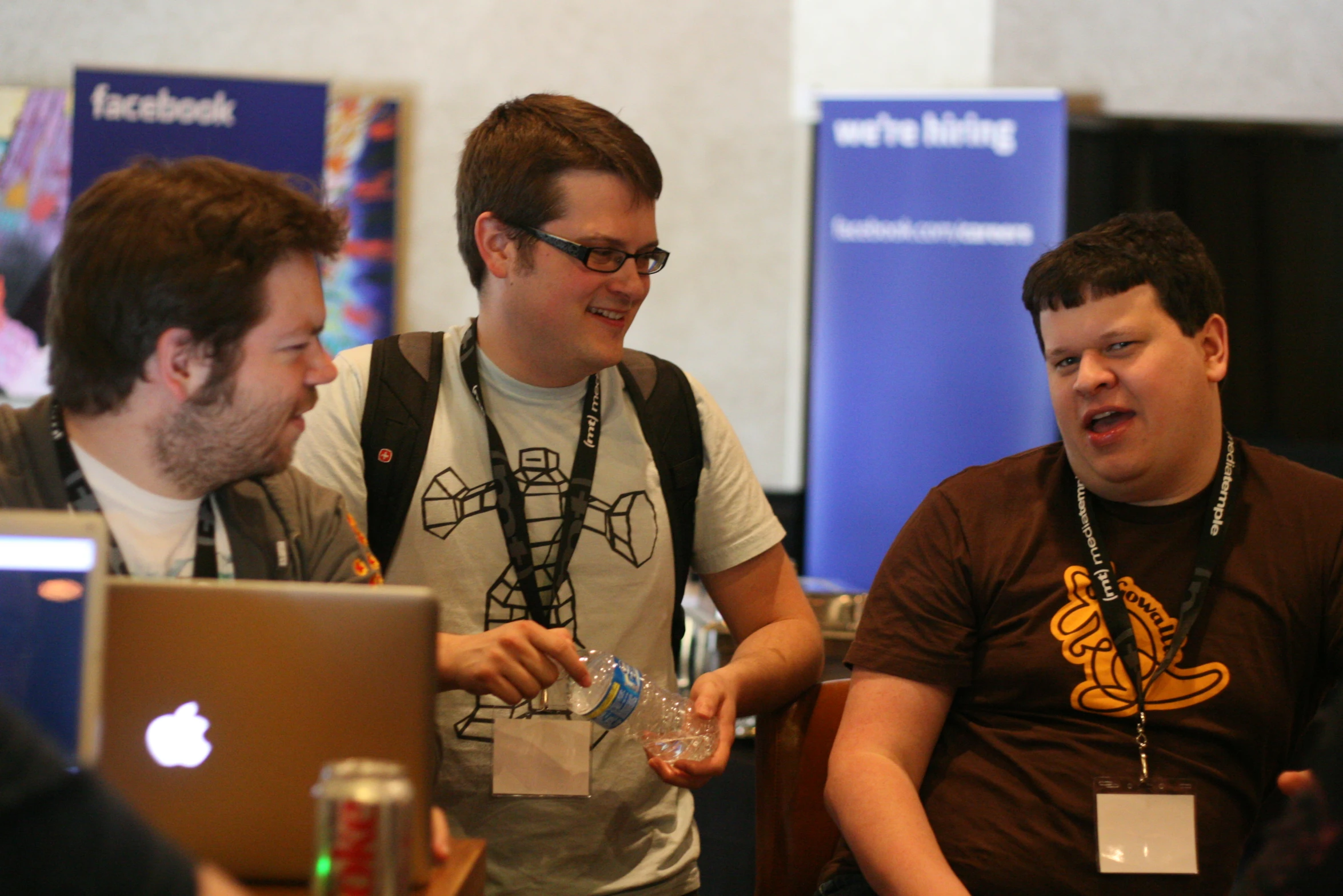 two men in tshirts talking and looking at soing on a lap top