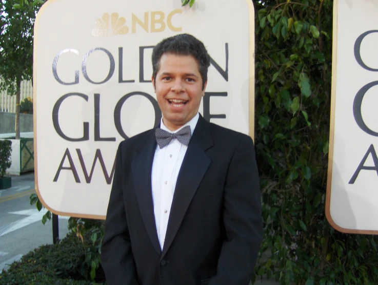 a young man wearing a black suit and bow tie