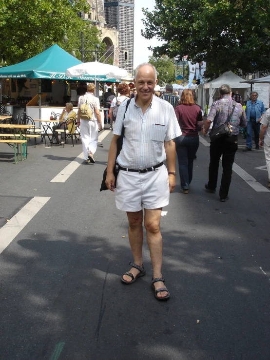 a man in white shorts and sandals walking down the street