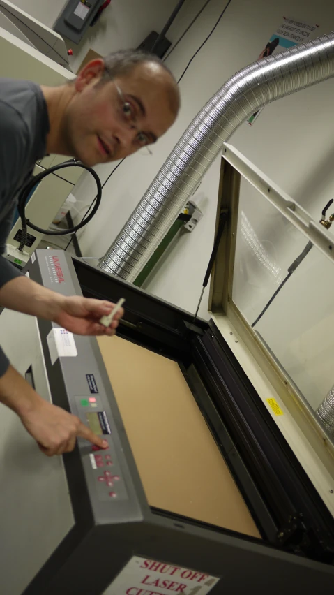 a man inspects the parts that are behind him in a machine