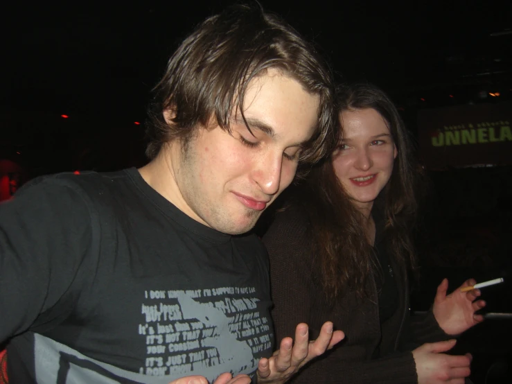 man smoking cigarette standing next to woman in dark room