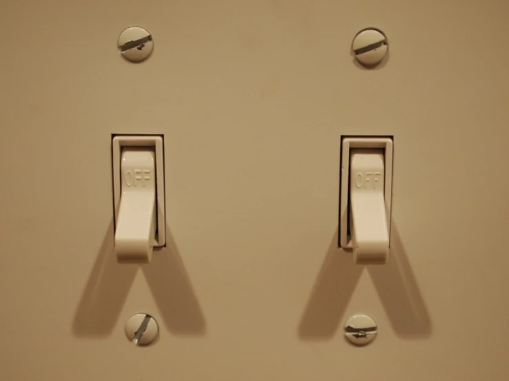 a beige wall with two dim lights and switches