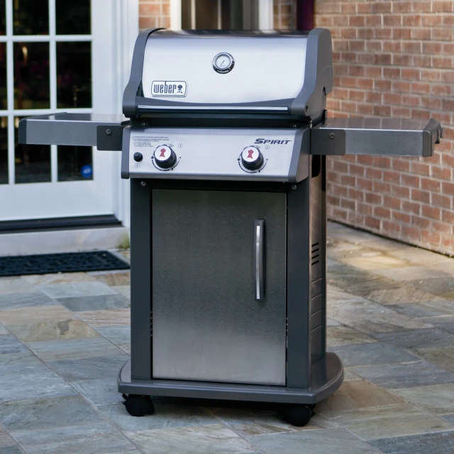 a black and silver grill on top of a brick patio