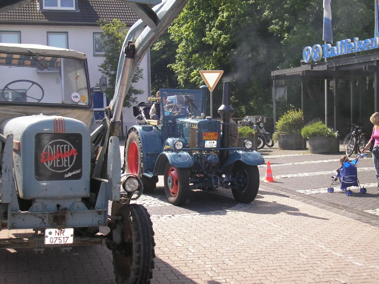 an old blue tractor with two sidecars parked in front of a large building