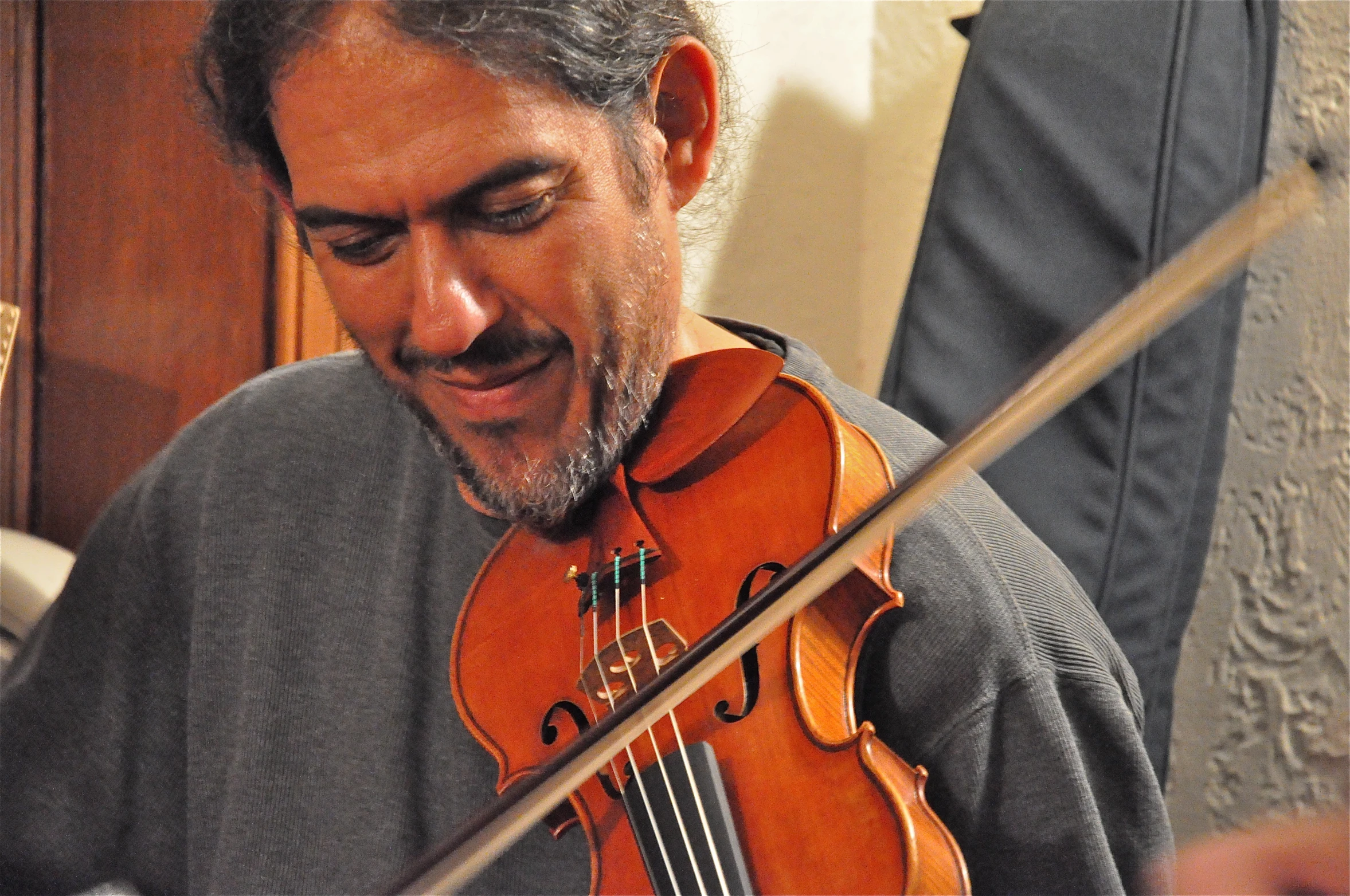 a man in grey sweater playing a violin