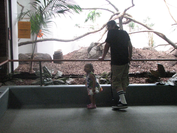 a man and his child are looking at an animal cage