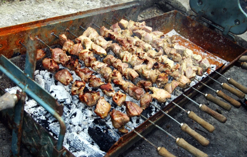 chicken cooking on an outdoor grill with grill tongs
