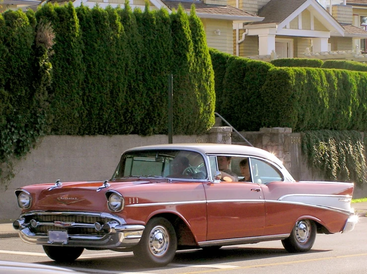 an older car traveling on the street near residential area