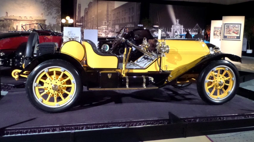 the antique yellow car is on display with the old model black car behind it