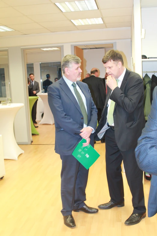 two men in suits stand together, talking