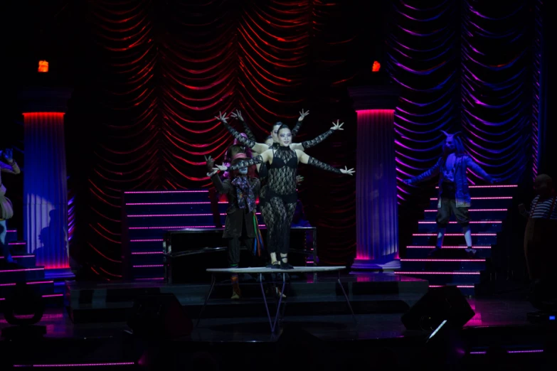 two performers with arms outstretched on stage at nighttime