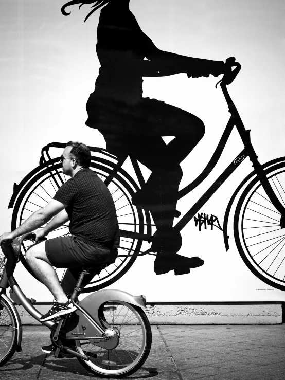 a man riding a bike past a painting of a person on a bicycle