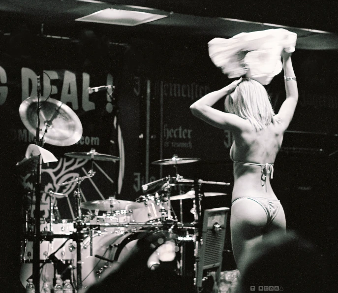 a  woman in a bikini on stage with drums and other musical instruments