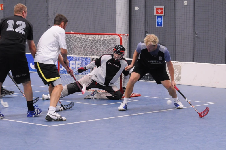 several men on a court playing hockey while the referees look on