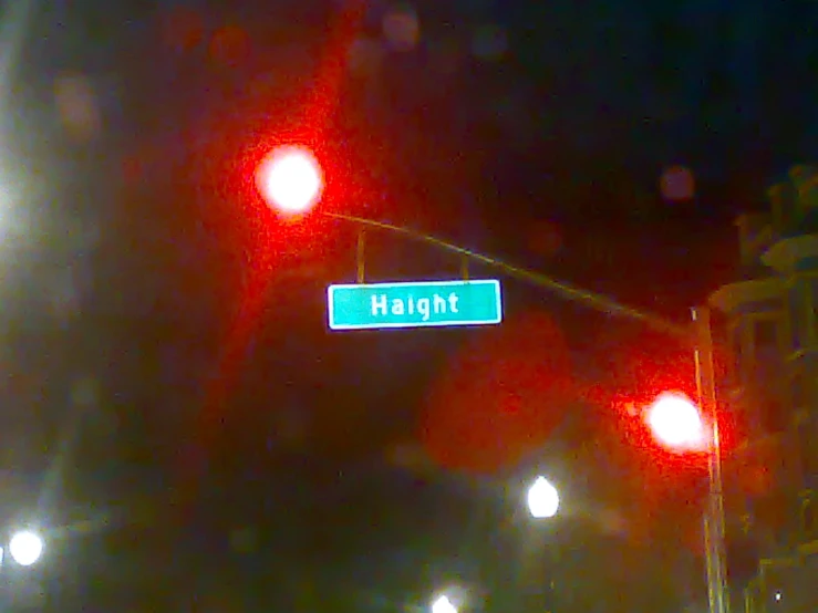a street sign with two red lights at night time