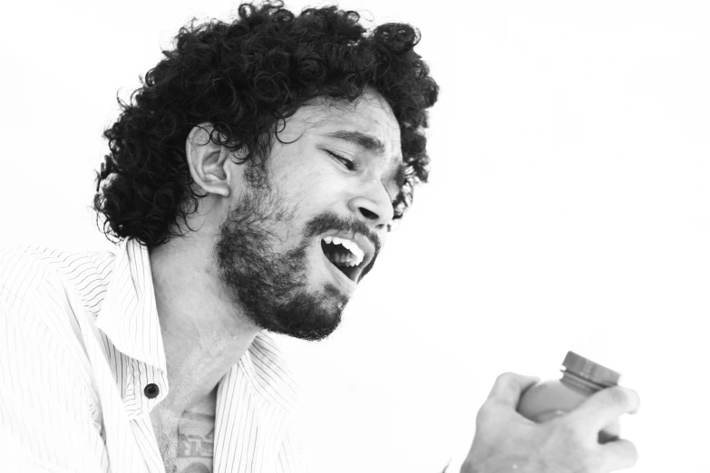 a man with curly hair laughing while holding an electronic device